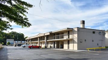 A multi-story motel with a parking lot, a red car parked in the lot, and a sign for 'SWAGAT' in the background.