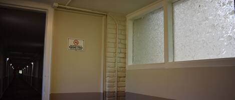 A smoke-free sign in a hallway with a brick wall and a window with frosted glass.