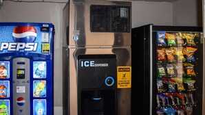 A vending machine with a Pepsi logo, an ice dispenser, and a caution sign warning about a slippery floor. - MHO Hotel Bordentown (Bordentown)