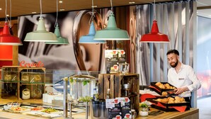 Un bufé de desayuno con diversas opciones de comida, una estación de café y una persona sirviendo.
