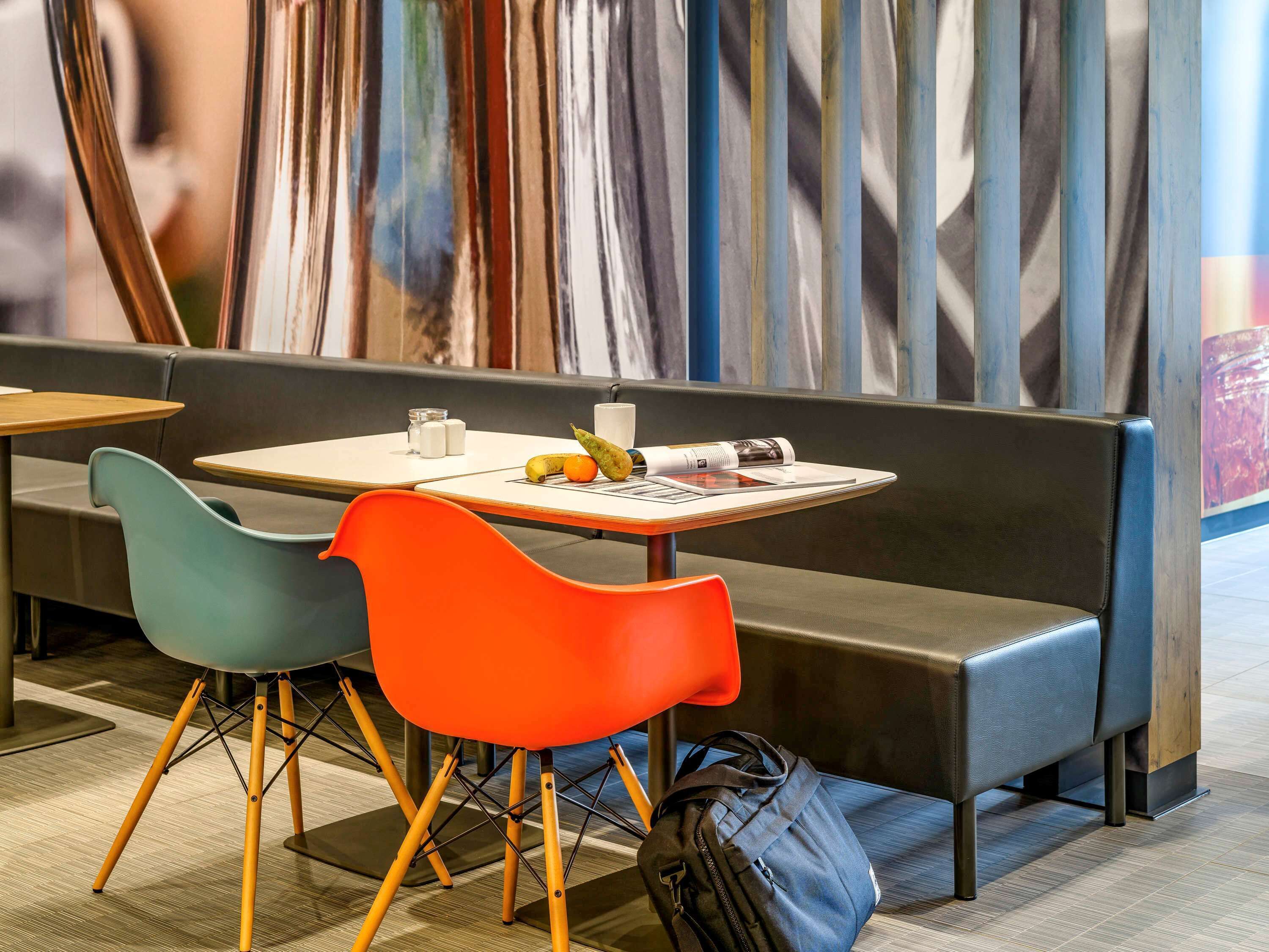 Il y a un espace détente avec une table, des chaises et un banc. Un sac est posé sur le sol.