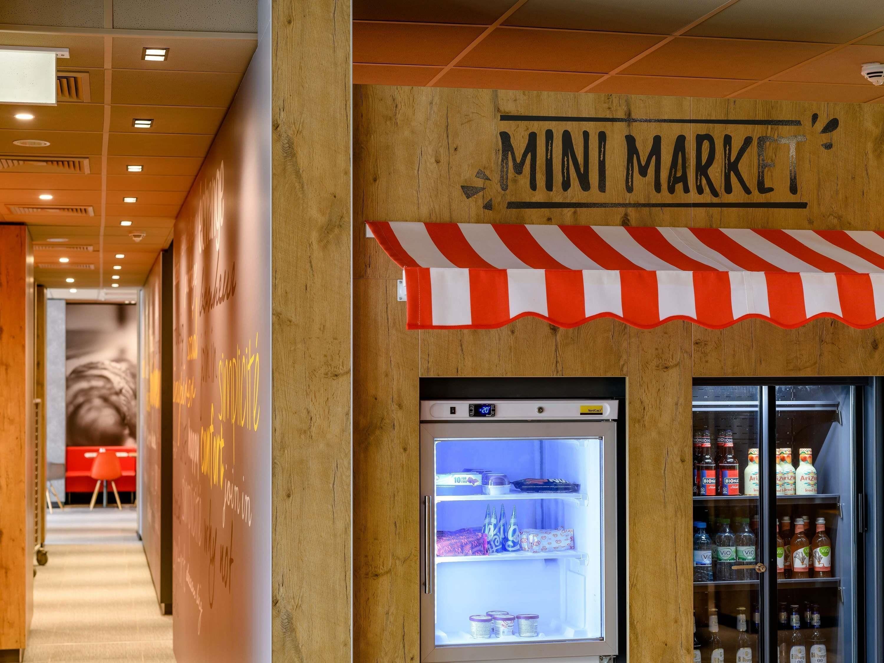 Un petit magasin avec un présentoir réfrigéré et une enseigne au-dessus.