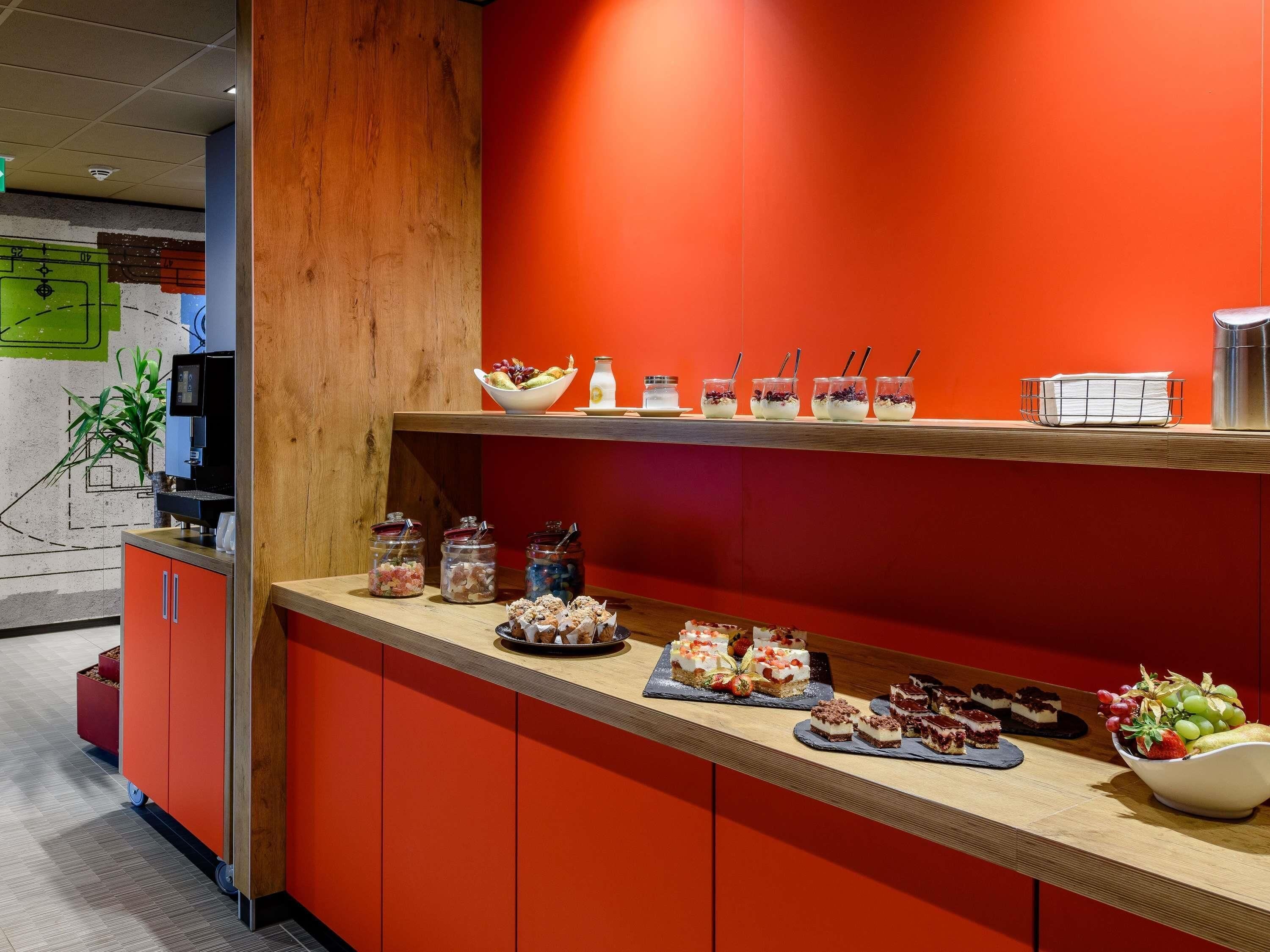 A buffet area with a variety of food items, including desserts and fruits, and a coffee machine.