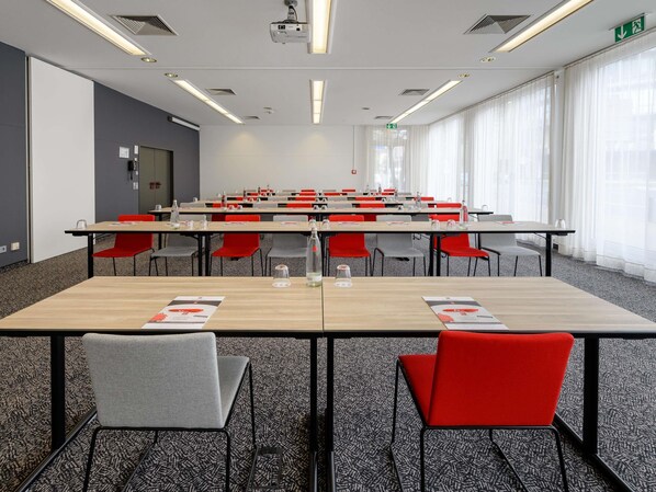 A conference room with tables, chairs, and a projector. - ibis Mainz City (Mainz)