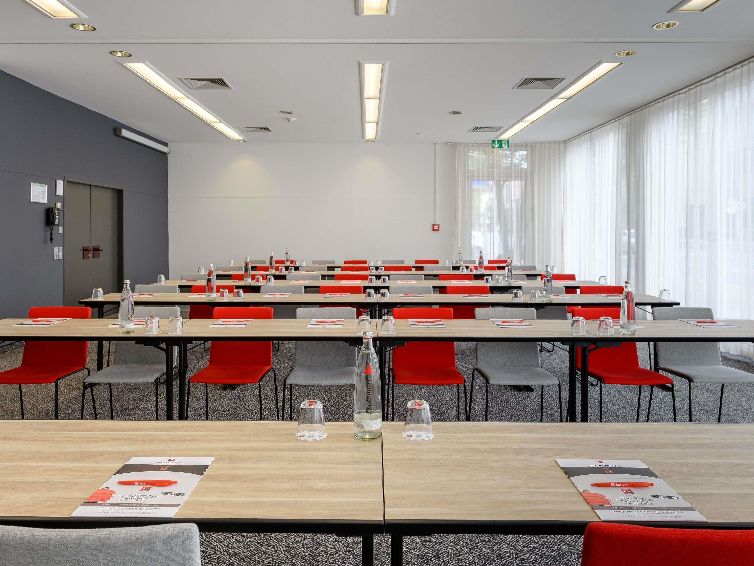 A conference room with multiple tables, chairs, and water bottles.