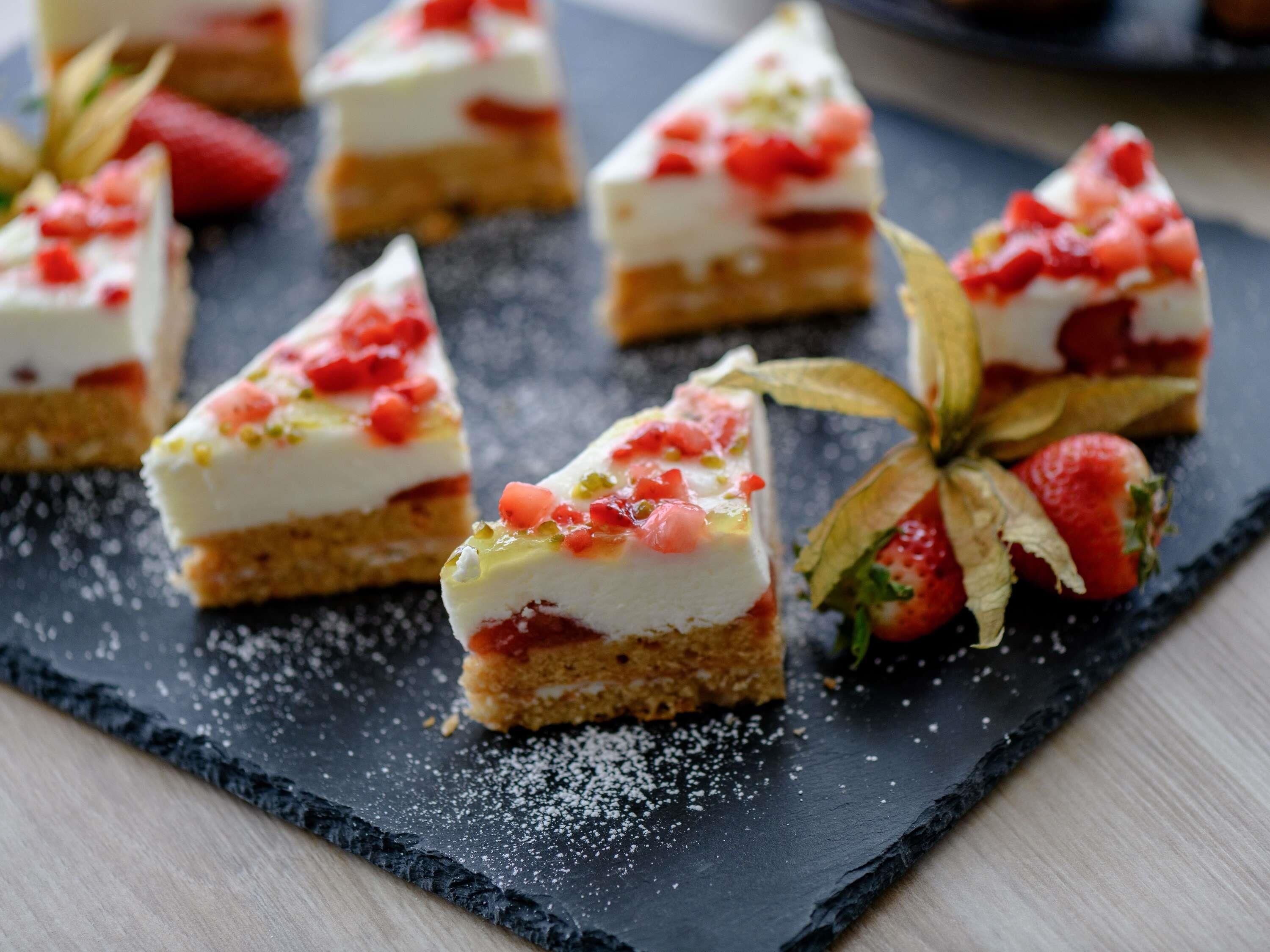 Un postre con fresas y crema sobre una tabla de pizarra.