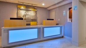 Una recepción de hotel con diseño moderno, un panel de vidrio y un letrero que indica zona para no fumadores.