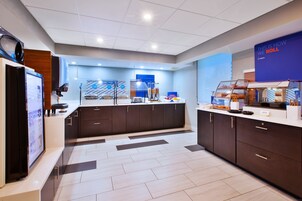 Una cocina de hotel moderna con zona de buffet, estación de café y una pantalla digital con información.