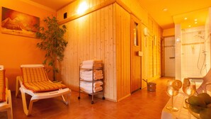 A spa room with wooden walls, a massage chair, a shelf with towels, and a shower area. - Best Western Plus Hotel Schwarzwald Residenz (Triberg im Schwarzwald)