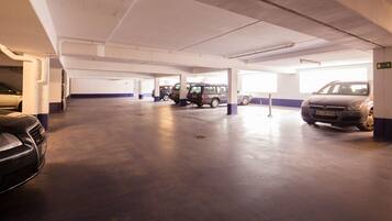 Un parking à plusieurs niveaux où sont garées plusieurs voitures, avec des planchers en béton et des murs blancs agrémentés de touches de bleu.