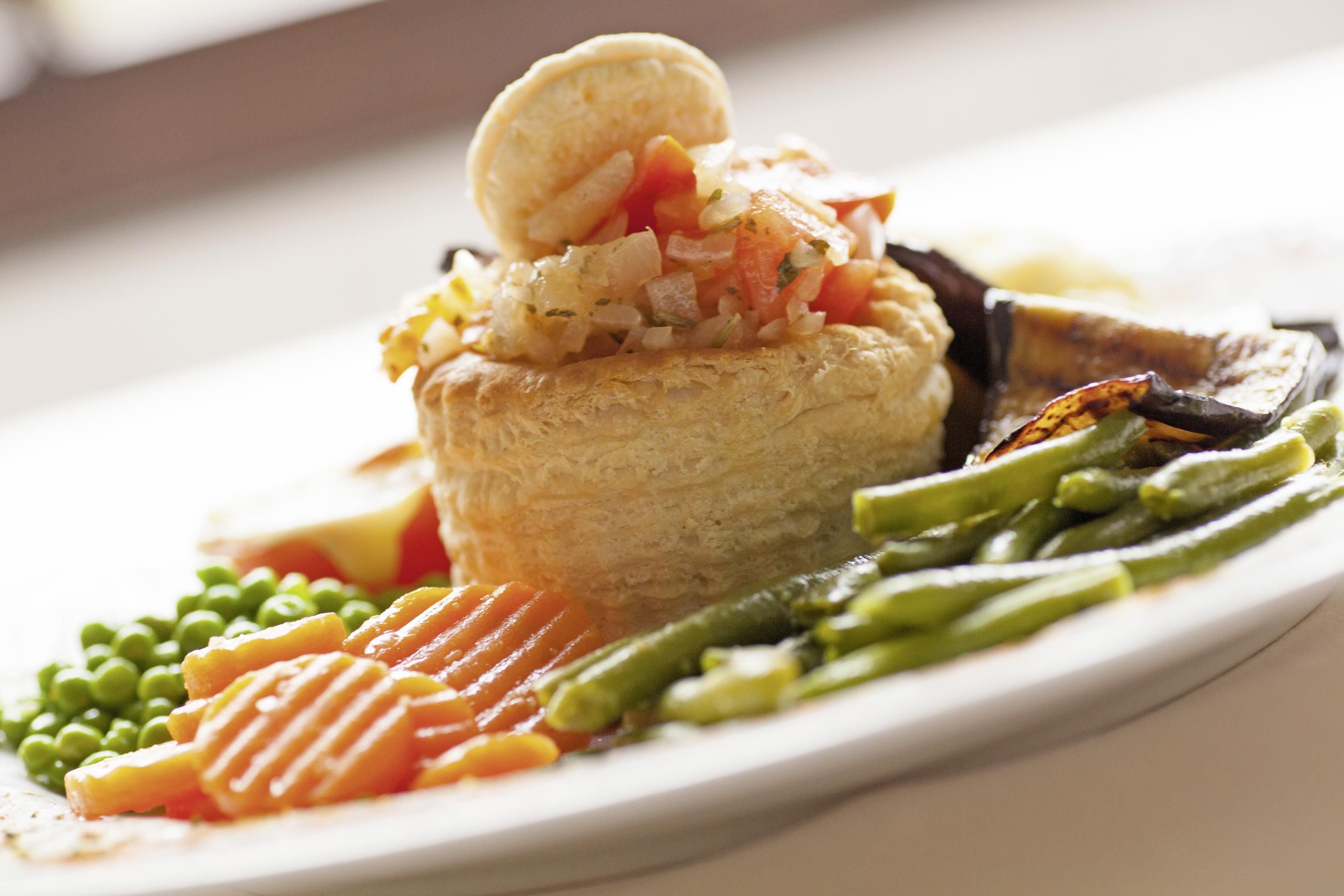 Un repas composé d’une pâtisserie, de légumes et d’un morceau de viande, le tout servi dans une assiette.