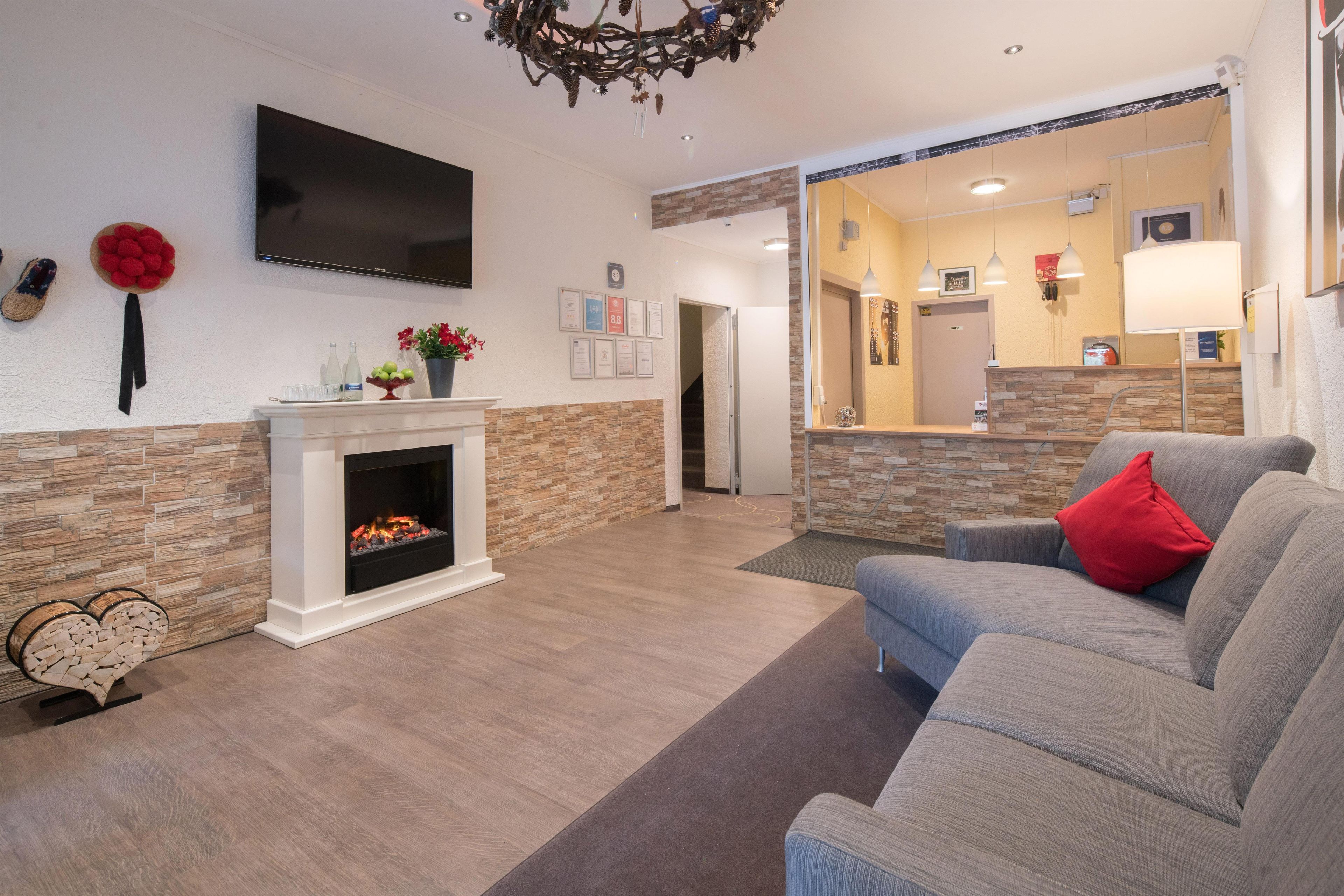 A modern living room with a fireplace, a flat-screen TV, and a sofa with a red pillow.