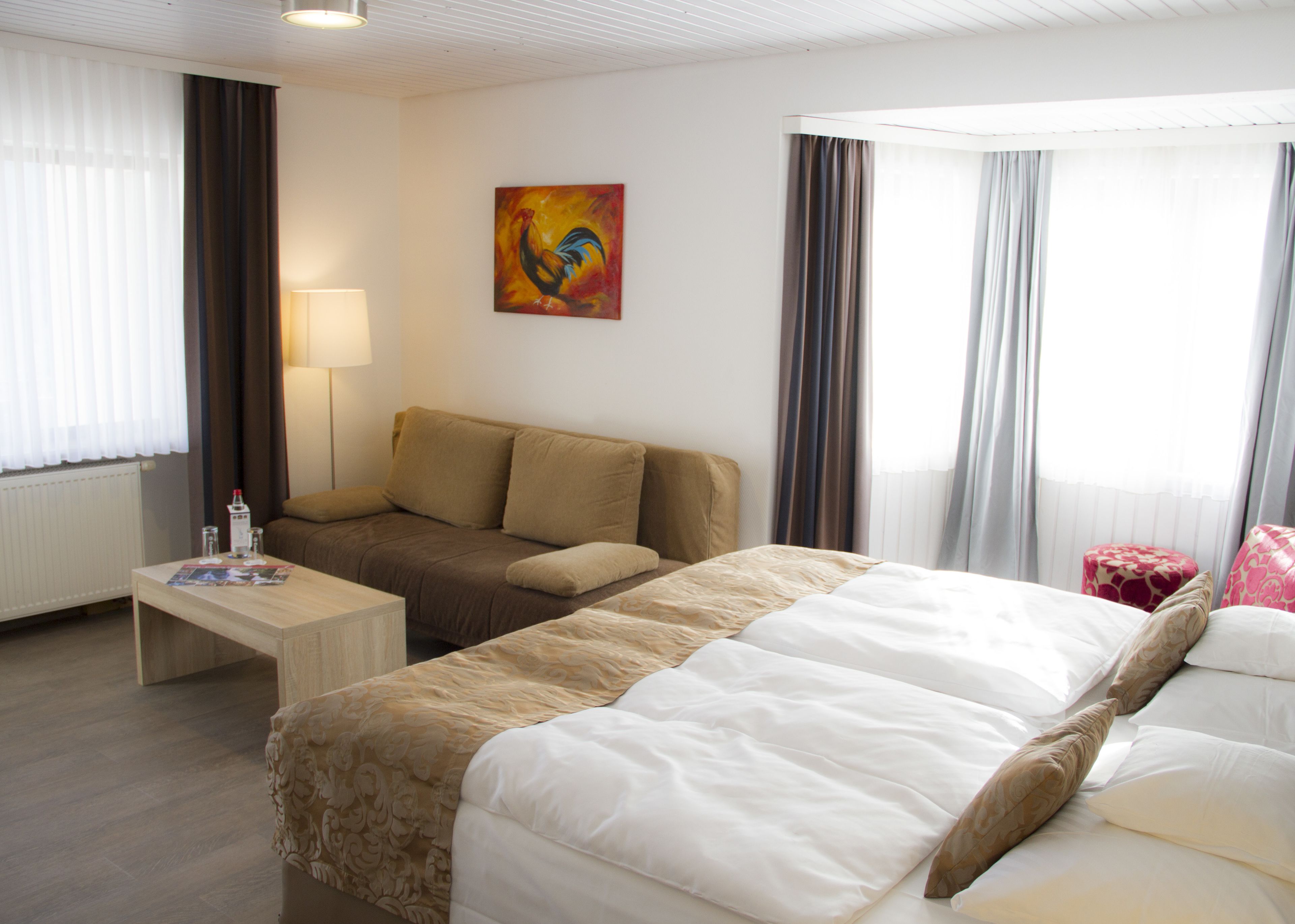 Una habitación de hotel con una cama, un sofá, una mesa con lámpara y un cuadro en la pared.
