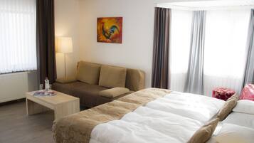 Una habitación de hotel con una cama, un sofá, una mesa con lámpara y un cuadro en la pared.