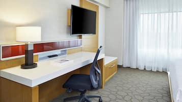 Ein Hotelzimmer mit Schreibtisch, Stuhl, Fernseher und Bett.