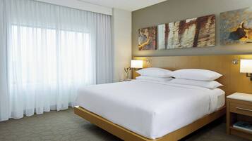 Une chambre d’hôtel avec un grand lit, des rideaux blancs et trois œuvres d’art accrochées au mur.