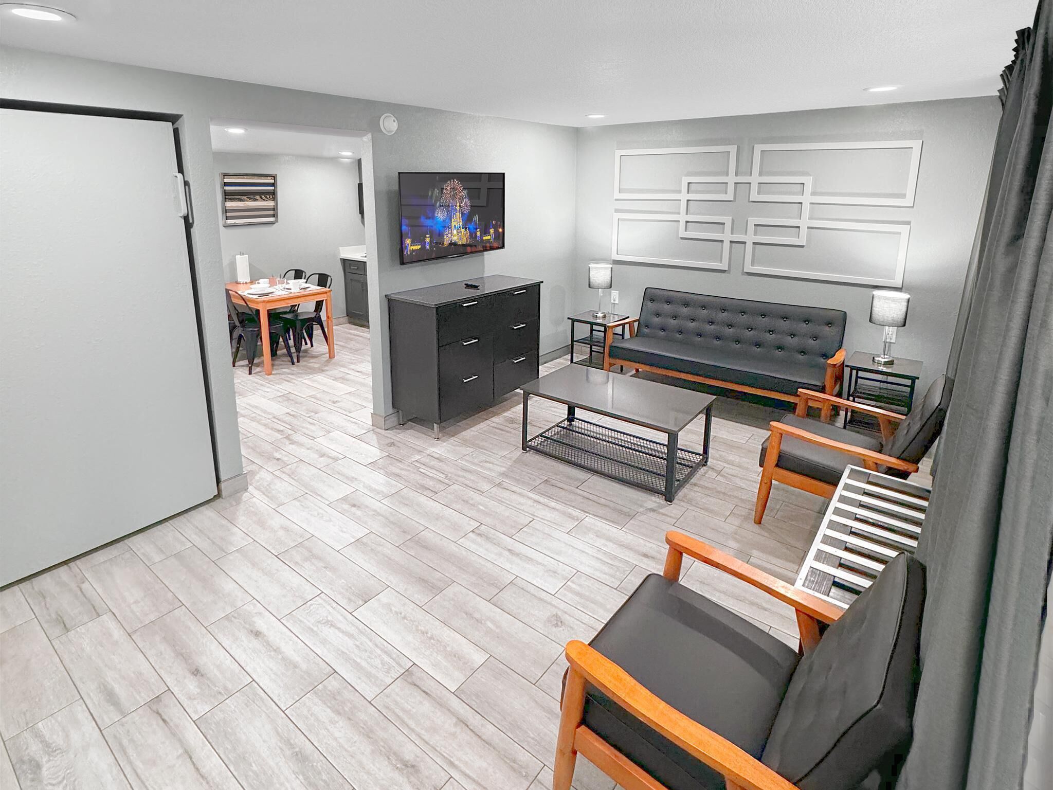 Una sala de estar moderna con un sofá, una mesa de centro y un televisor. Hay un comedor con una mesa y sillas.