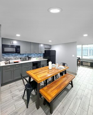 Una cocina moderna con armarios grises, una mesa de comedor de madera y un horno empotrado.