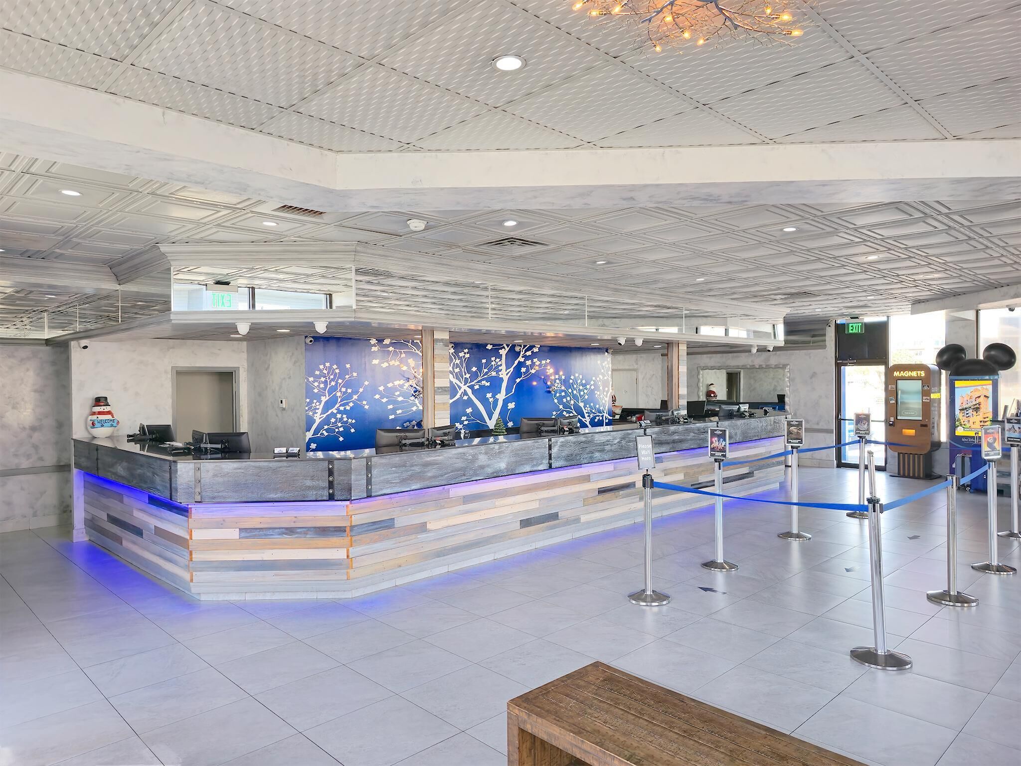 A spacious lobby with a reception desk, a blue wall mural, and a clear exit sign.