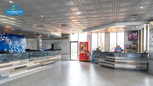 Eine großzügige Lobby mit modernem Design, inklusive einer Rezeption, einem großen digitalen Bildschirm und einer Sitzecke mit blauer Wanddekoration.