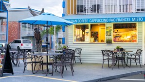 Ein Außenbereich mit Tischen und Stühlen vor einem Café namens 'Cuban Coffee Cappuccino Pao Frances Misto'.