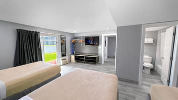 Una camera d'albergo con due letti, televisione, bagno e vista sull'esterno.