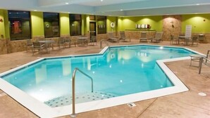 Una piscina interior con agua cristalina, rodeada de sillas y mesas de descanso.