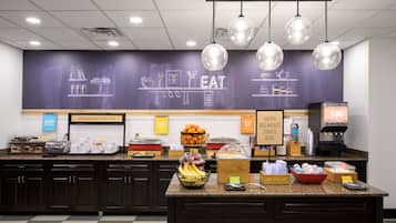 Una colazione a buffet con un menu scritto su lavagna, una macchina per il caffè e diversi cibi.