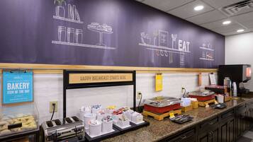 A breakfast area with a chalkboard wall displaying food items and a sign that says "HAPPY BREAKFAST STARTS HERE".