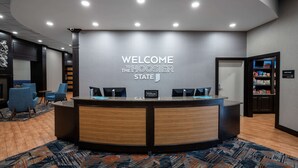 A reception desk with a "Welcome to the Hoosier State" sign, two monitors, and a "Hilton Honors" badge.