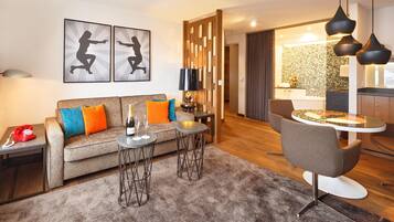 A modern living room with a sofa, two side tables, a coffee table, and a dining area with a chair and table.