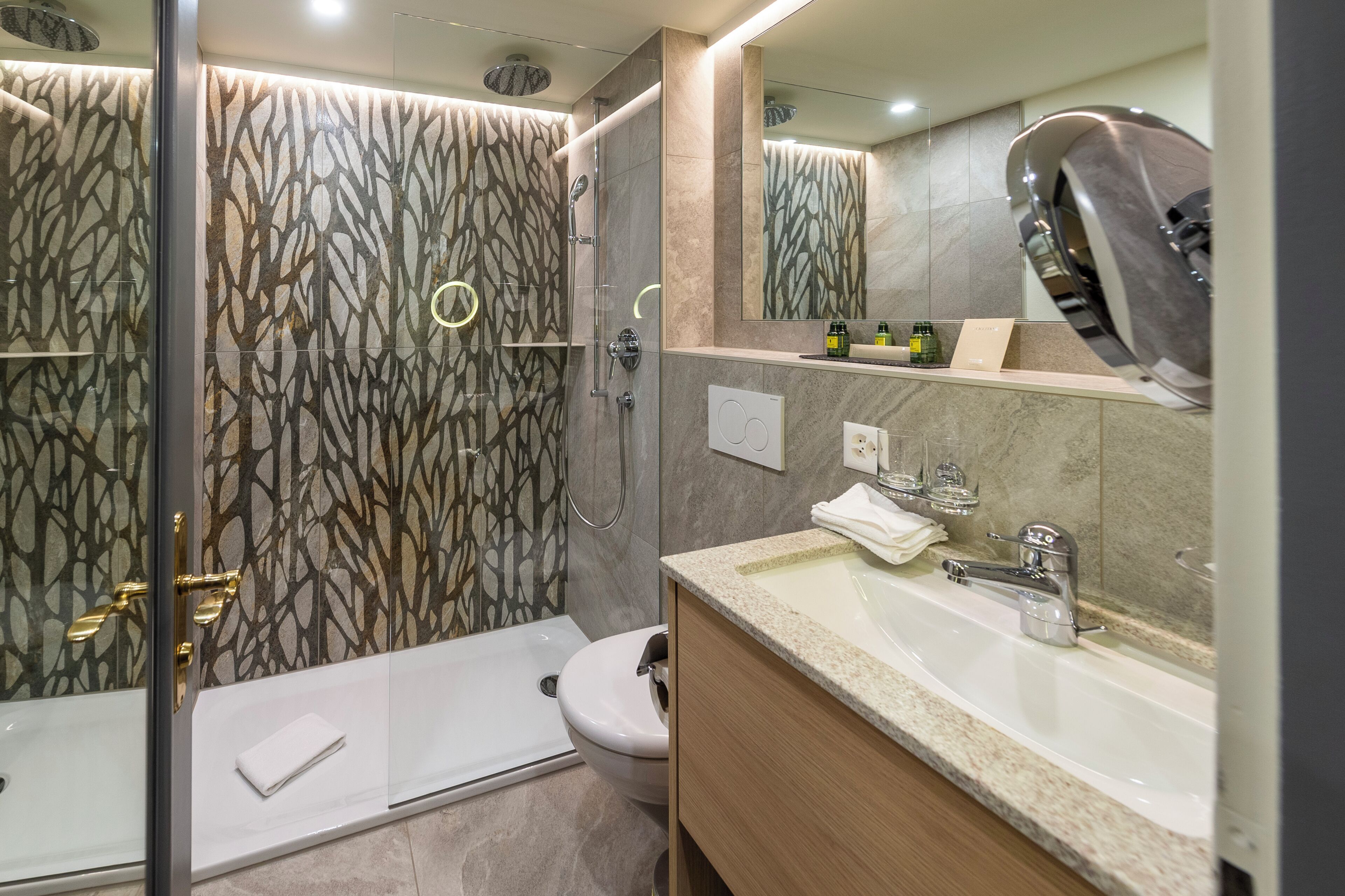 A modern bathroom with a glass-enclosed shower, a toilet, and a sink with a mirror above it.