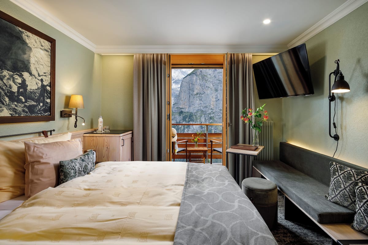 Une chambre dâhĂŽtel avec un lit, un coin salon, une tĂ©lĂ©vision et une vue sur la montagne.