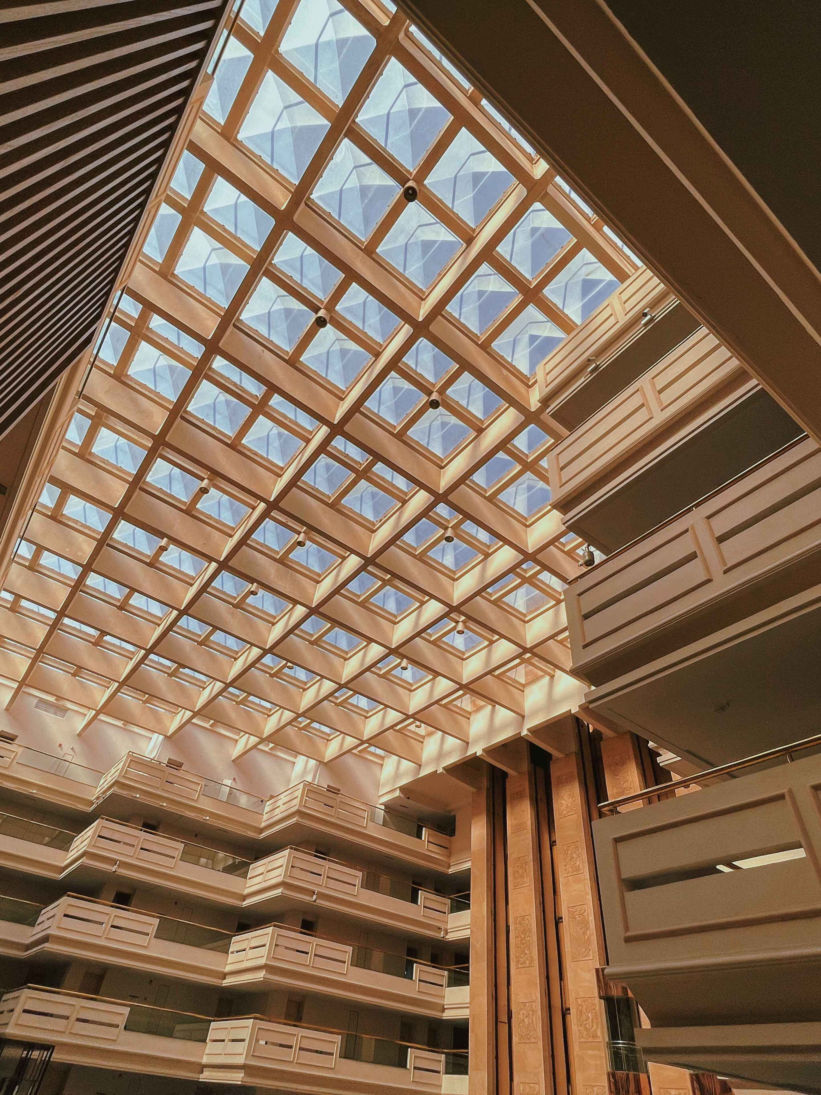 A modern building with a geometric glass ceiling structure, multiple balconies, and a clean, contemporary design.