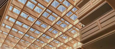 A modern building with a geometric glass ceiling structure, multiple balconies, and a clean, contemporary design.