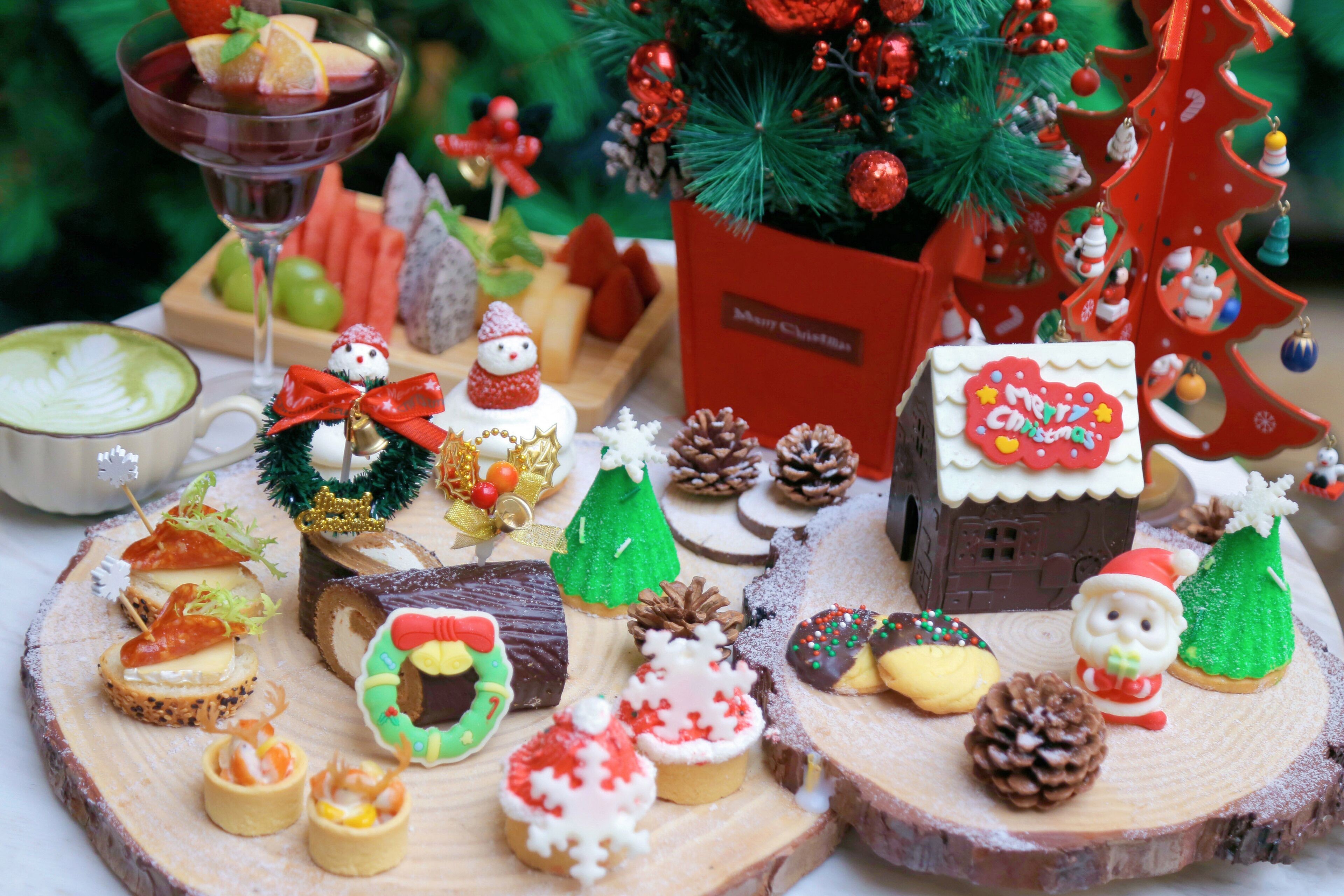 A festive table setting with various desserts, a Christmas tree, and a small Santa figurine.