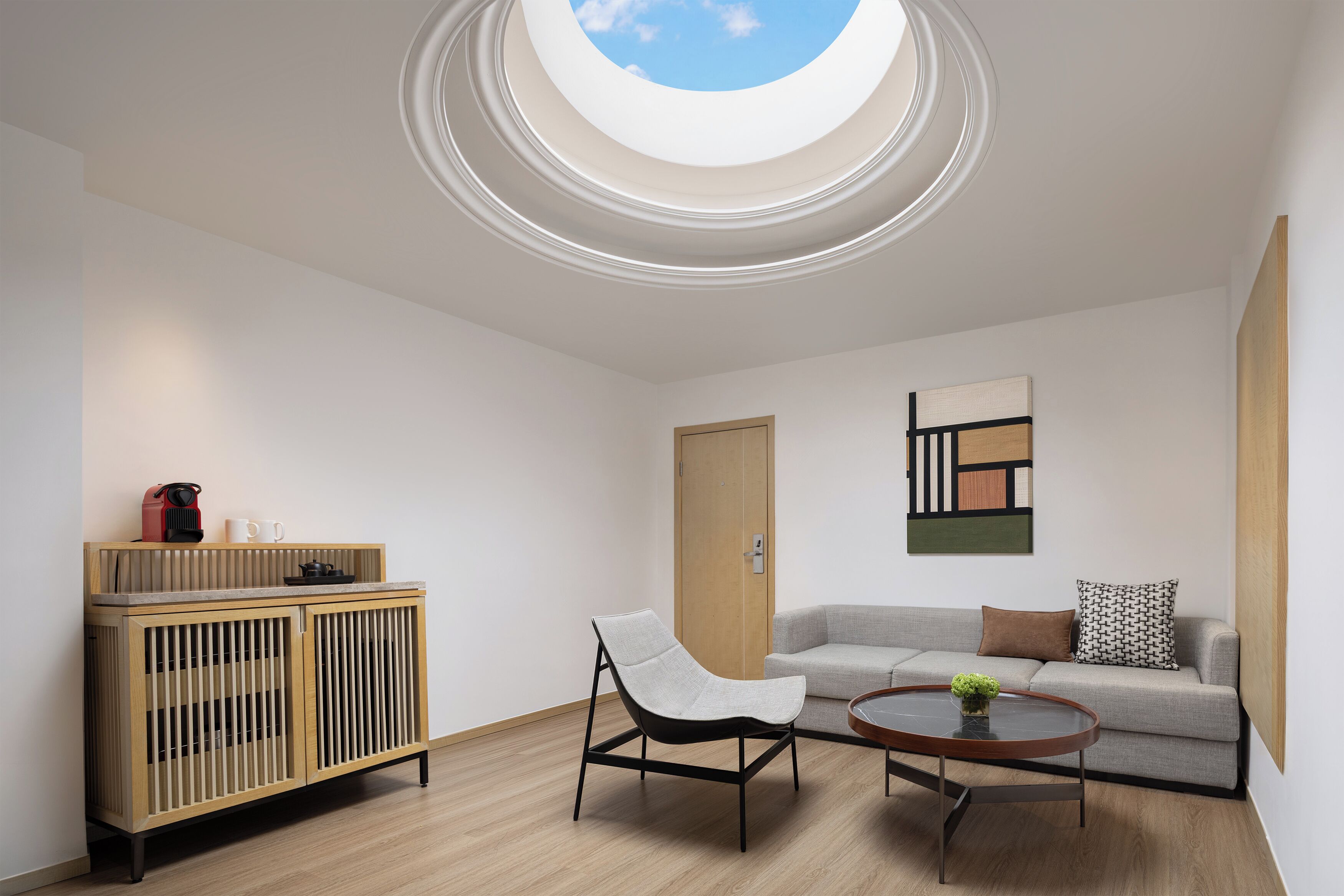 A modern living room with a skylight, a sofa, a chair, a coffee table, and a wooden cabinet.
