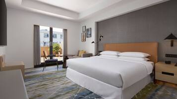 A hotel room with a large bed, a desk, a chair, and a view of the outside.