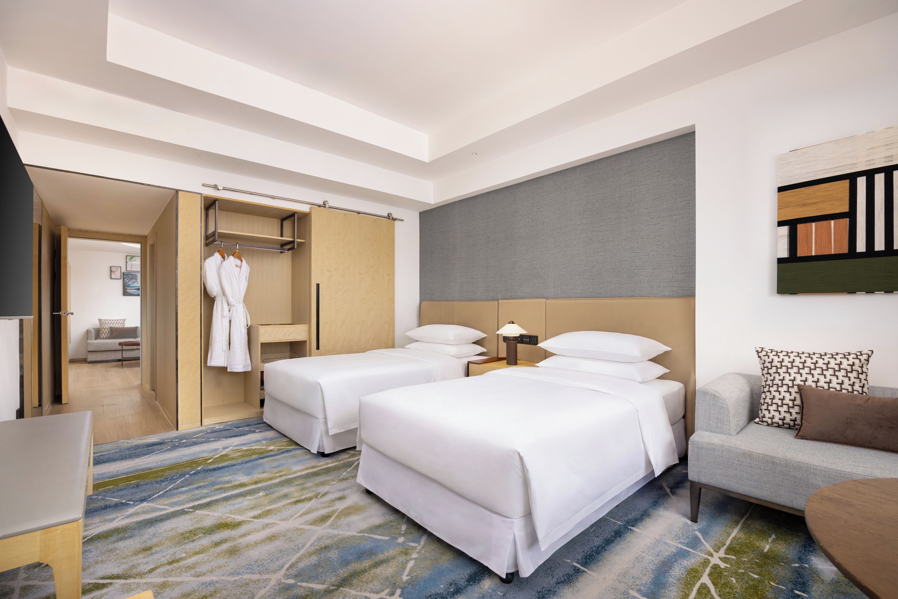 A hotel room with two beds, a sofa, a desk, and a wardrobe.