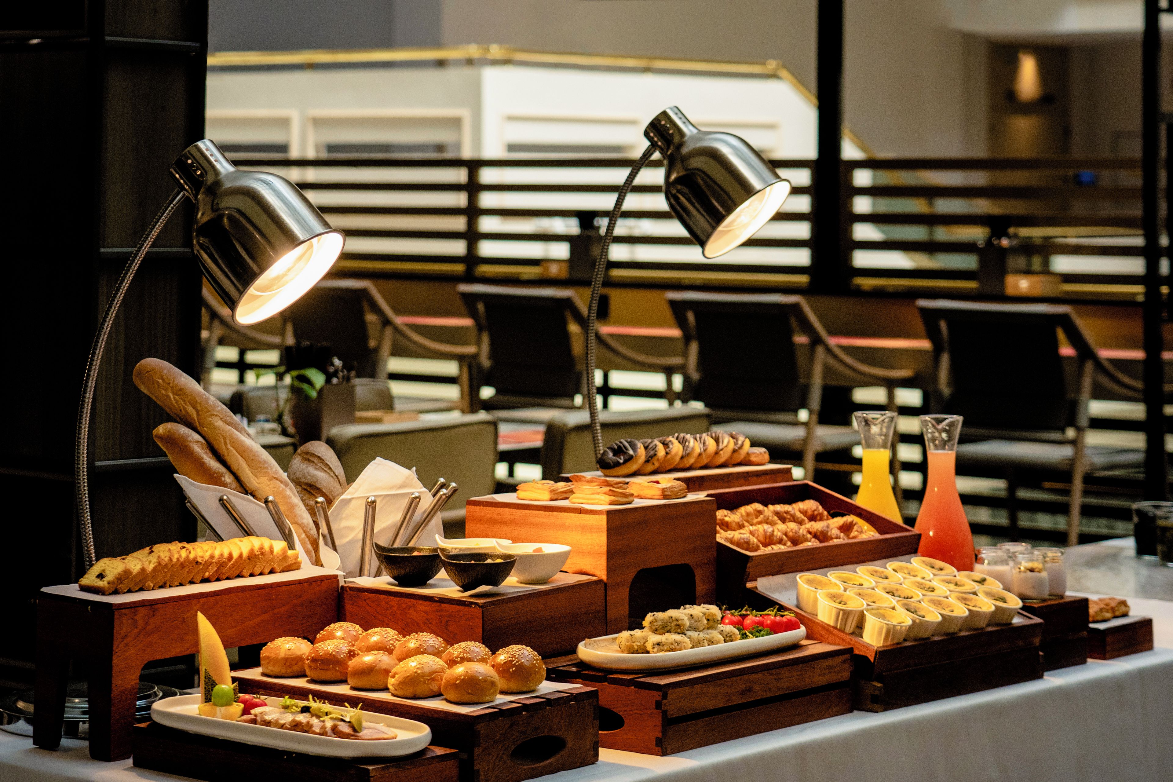 A buffet table with various food items and drinks, illuminated by overhead lamps.
