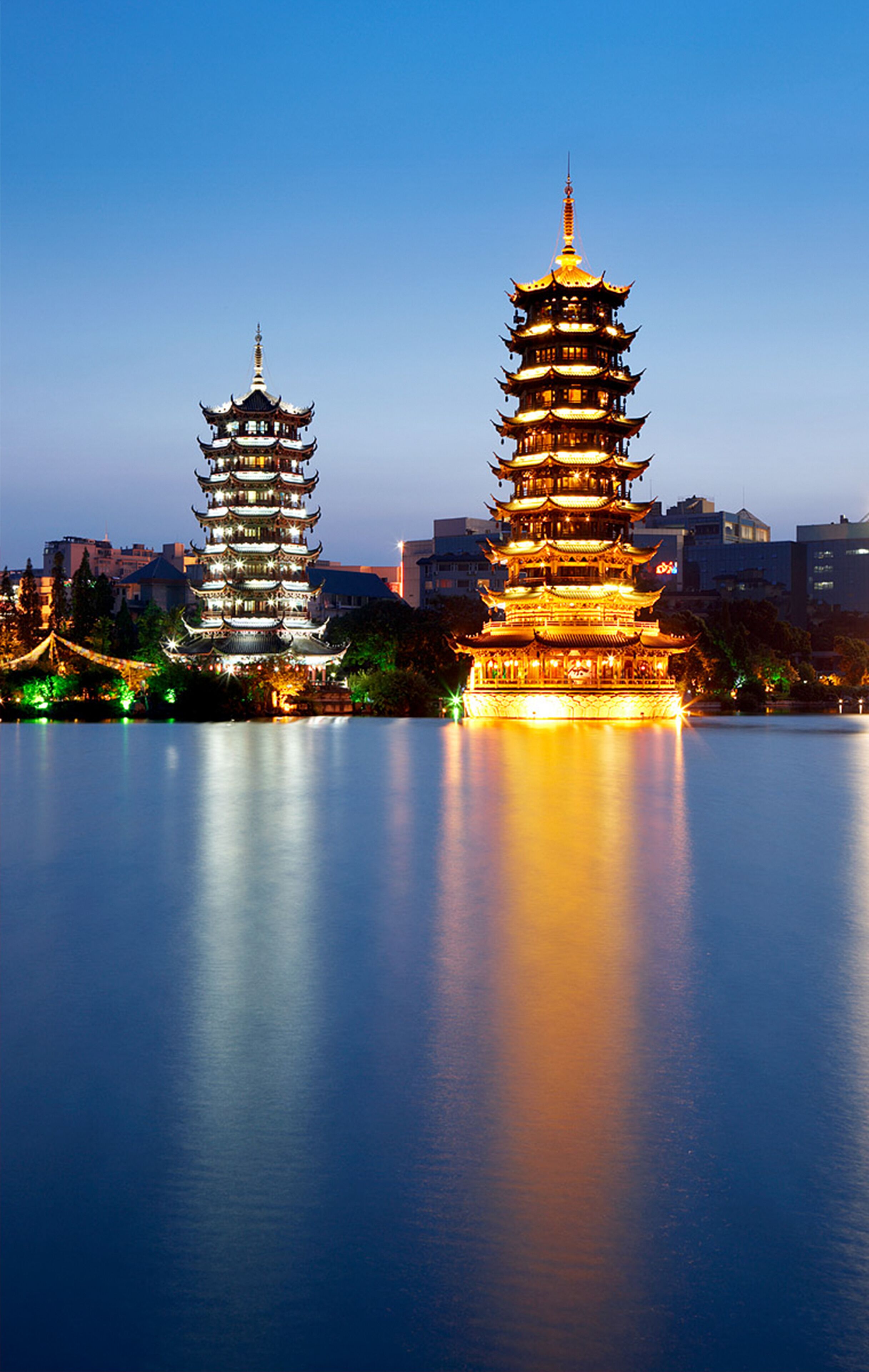 Dos pagodas iluminadas junto a un cuerpo de agua tranquilo.