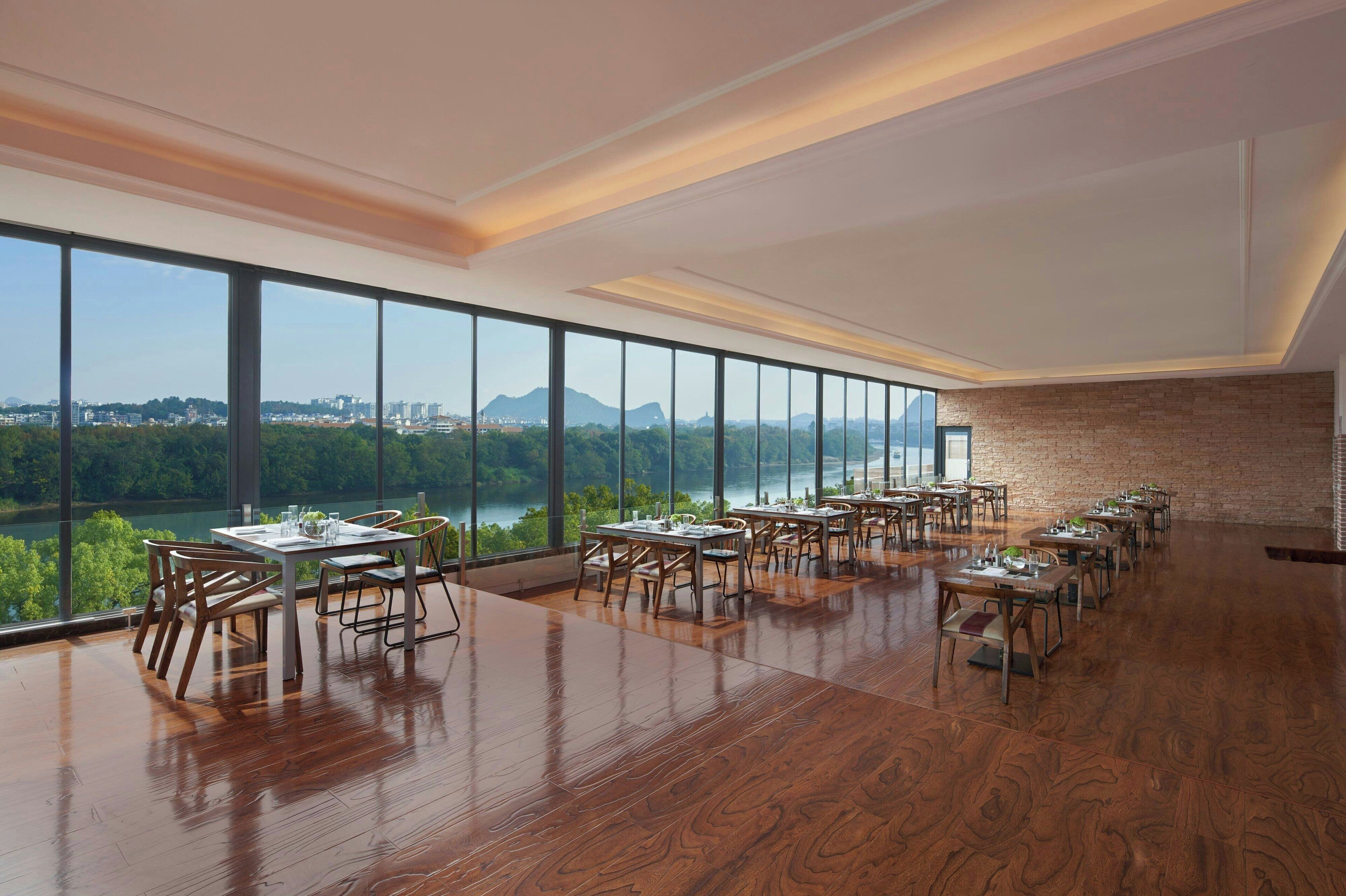 A spacious dining area with large windows offering a view of a lake and cityscape.