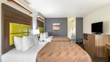 Ein Hotelzimmer mit einem großen Bett, einem Fernseher, einem Schreibtisch und einem Sessel.