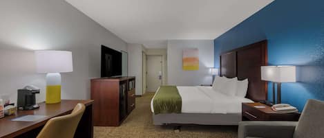 A hotel room with a bed, desk, chair, and a television.