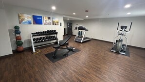 Een sportschool met trainingsapparatuur, gewichten en een loopband.