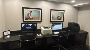 Een vergaderruimte met twee bureaus, elk voorzien van een computer, een printer en een stoel.