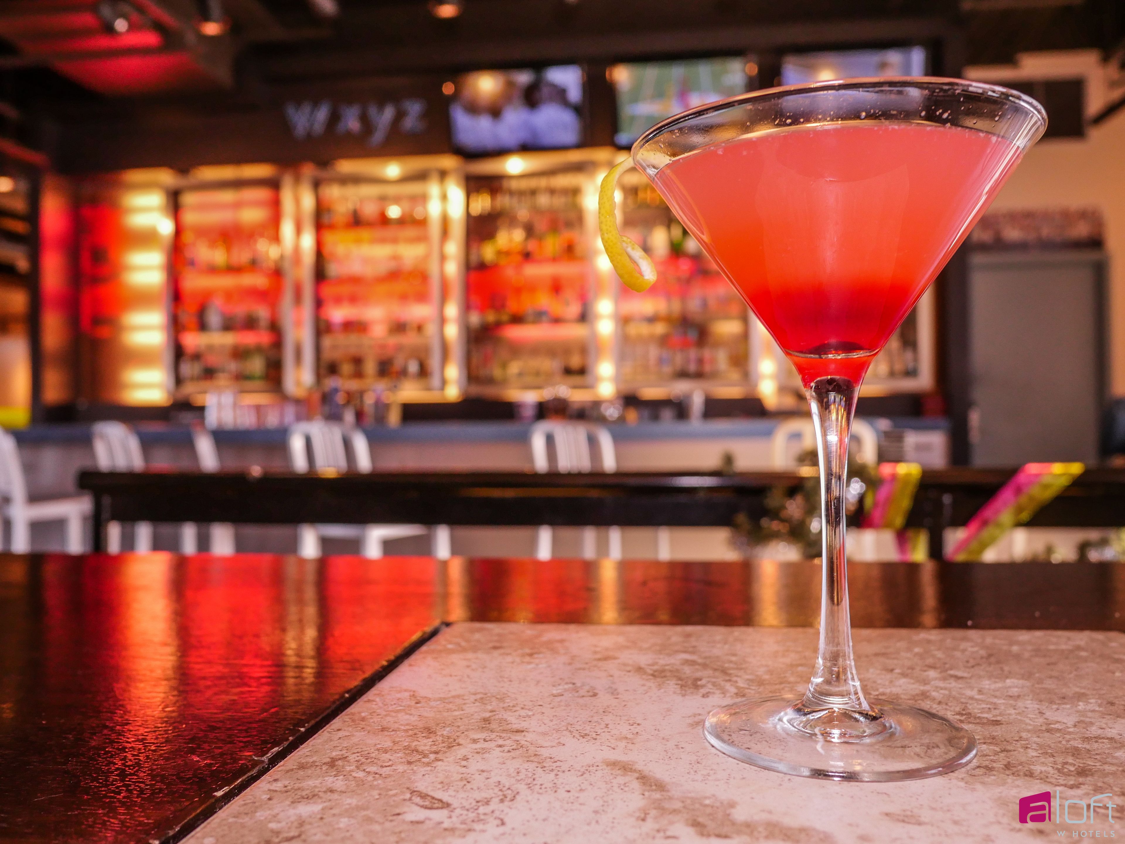A martini glass with a lime twist on a bar counter.