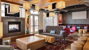 A modern lounge area with a fireplace, comfortable seating, and a projector screen. - Aloft by Marriott Tucson University (Tucson)