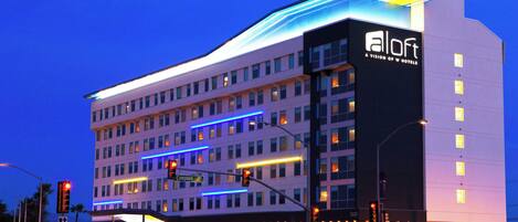 A multi-story hotel with a modern design, featuring a prominent 'aloft' sign and illuminated windows.