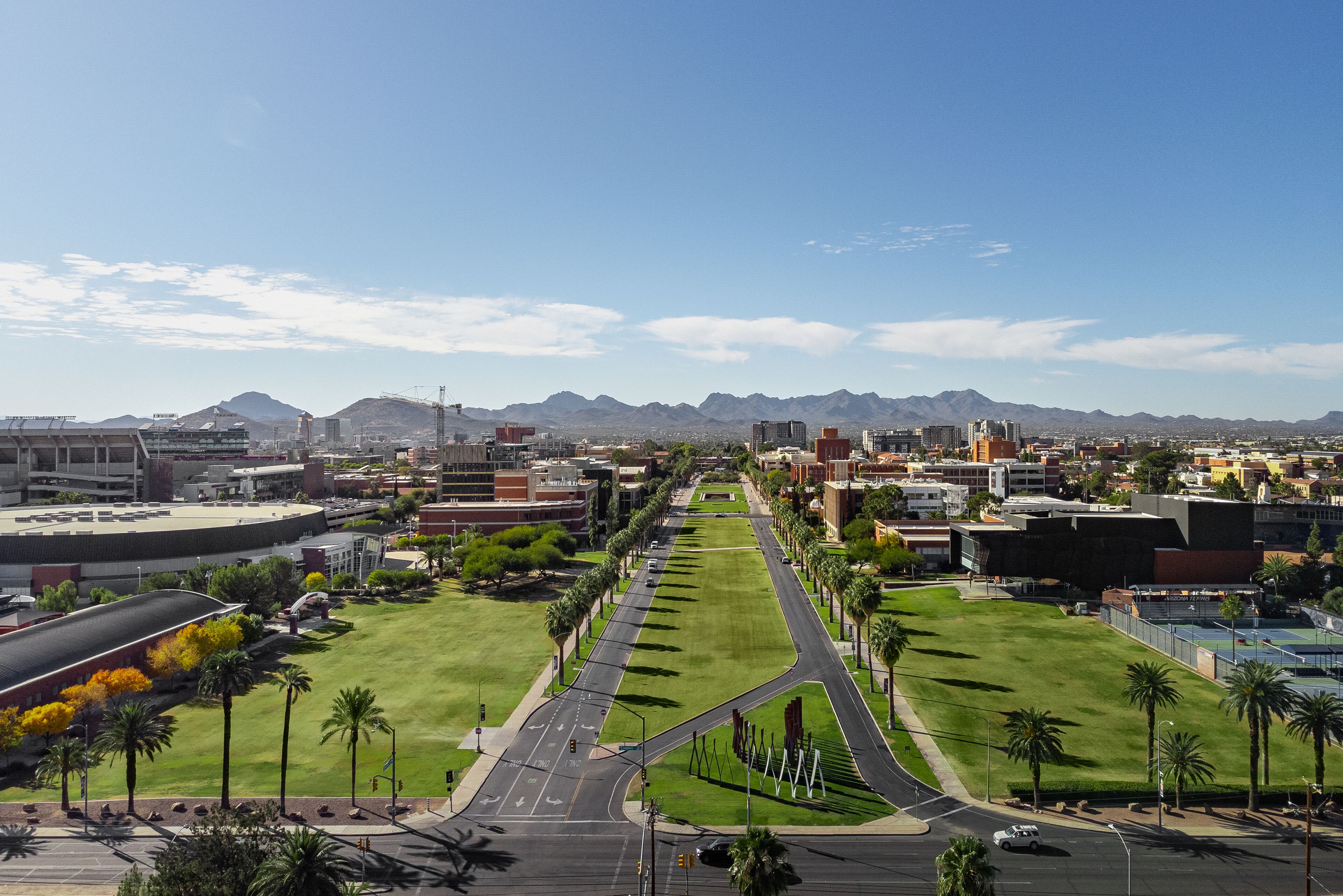 A cityscape with a wide road, green spaces, and buildings.